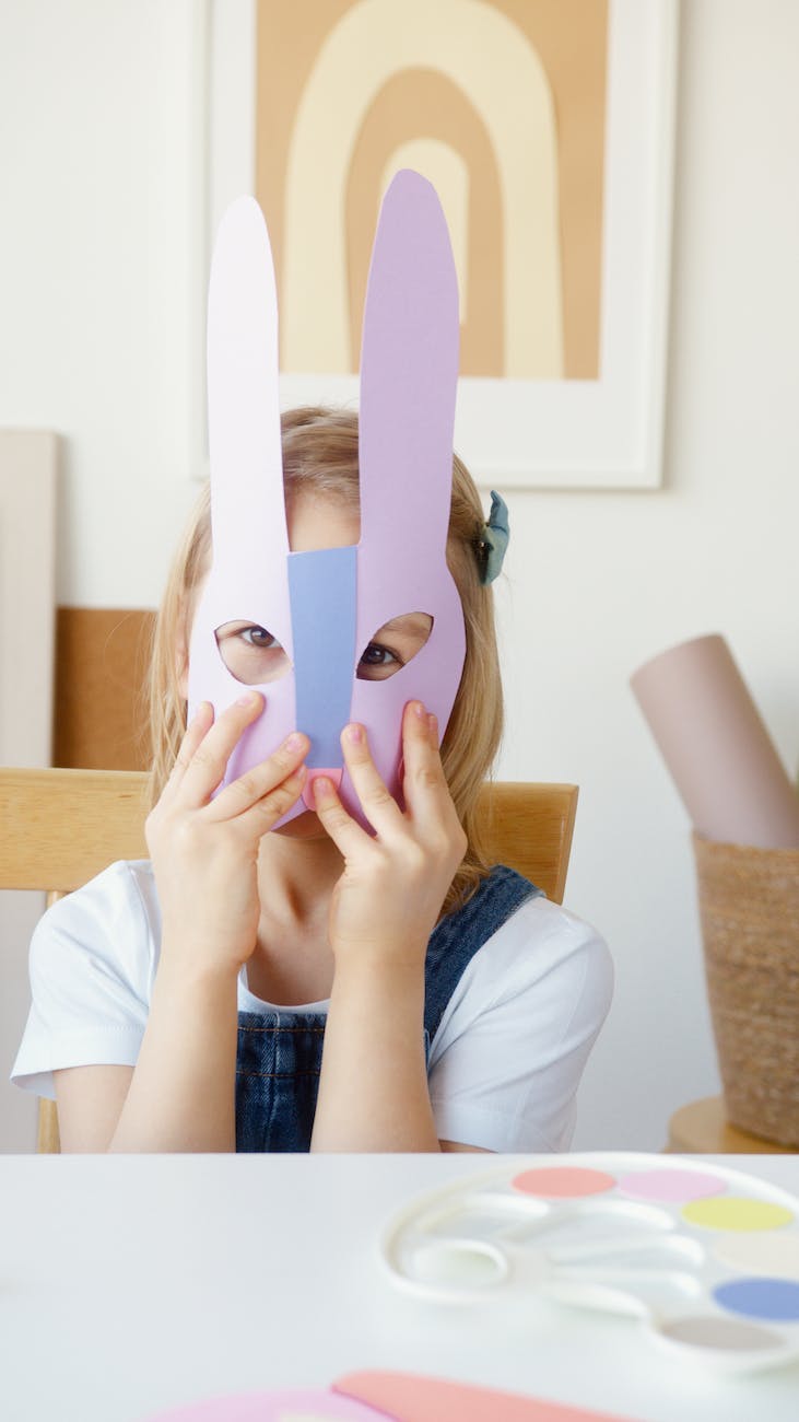 girl covering her face with a cutout animal mask