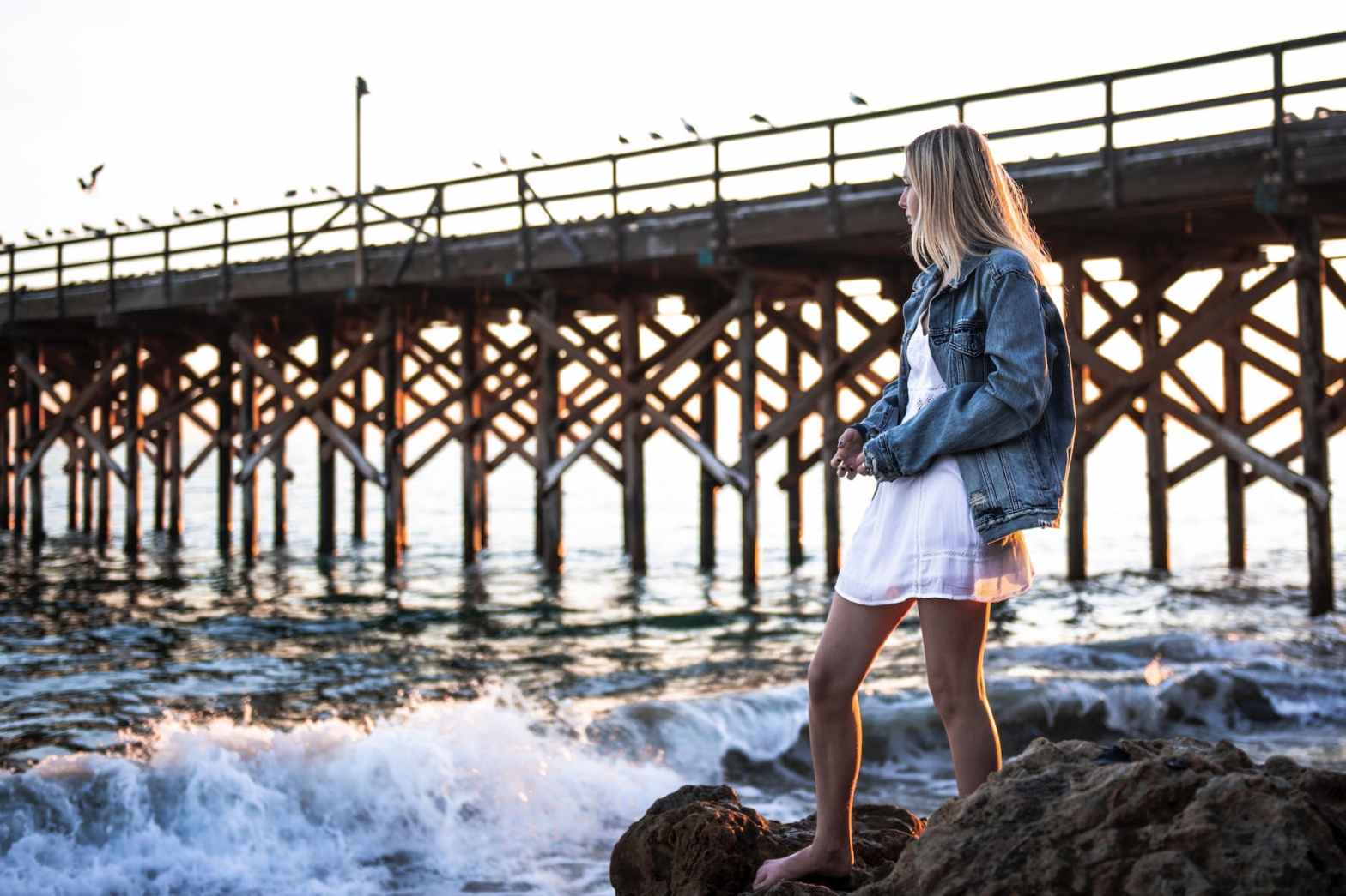 photo of woman standing on rock near sea